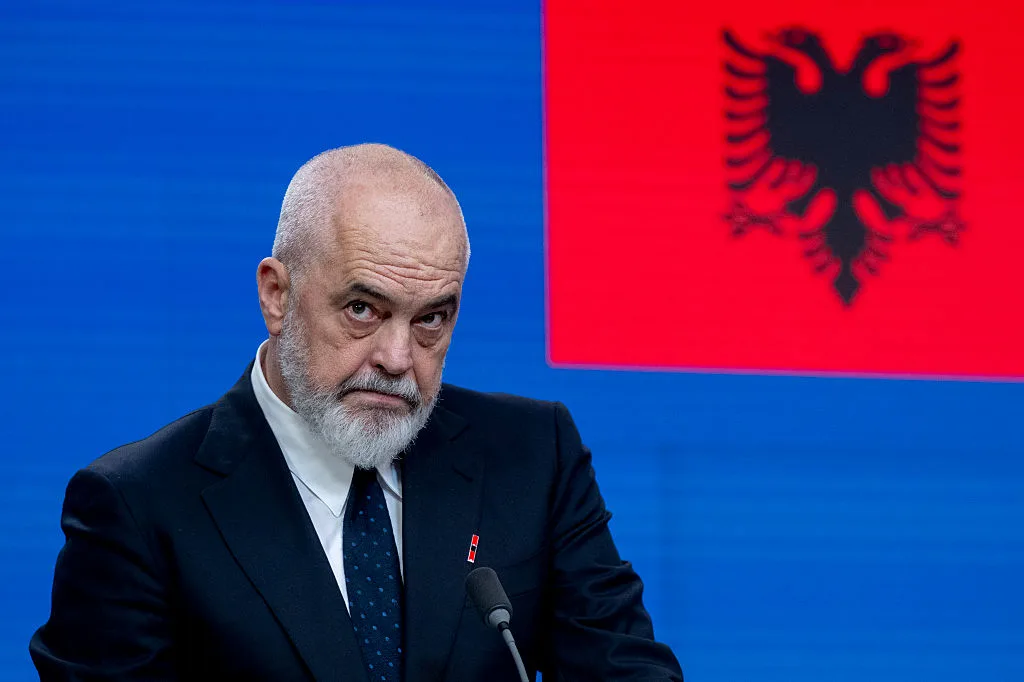 Edi Rama talking, with albanian flag in the background