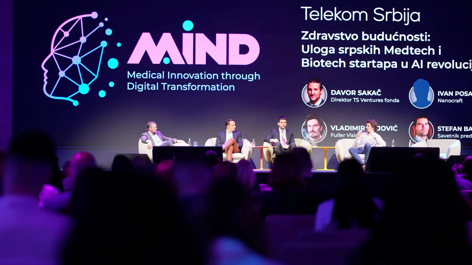 Four men sit on a MIND stage before an audience, backed by Telekom Srbija branding and Serbian medtech panel text.